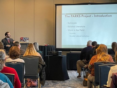 Ross Edelstein stands in front of a room of NAI conference attendees with a PowerPoint slide showcasing an introduction to the P.A.R.K.S project. 