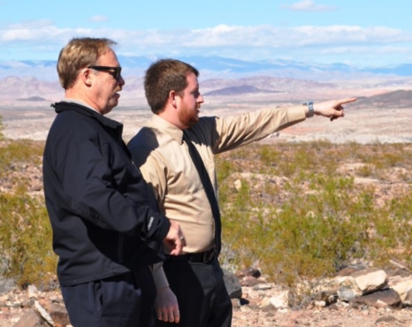 Two people in a wilderness setting, with one person pointing to the right