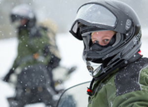 Two snowmobile riders with helmets and winter gear