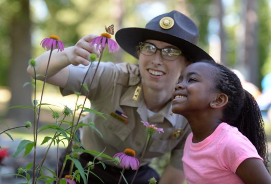 A park ranger looking at flowers with a smiling girl